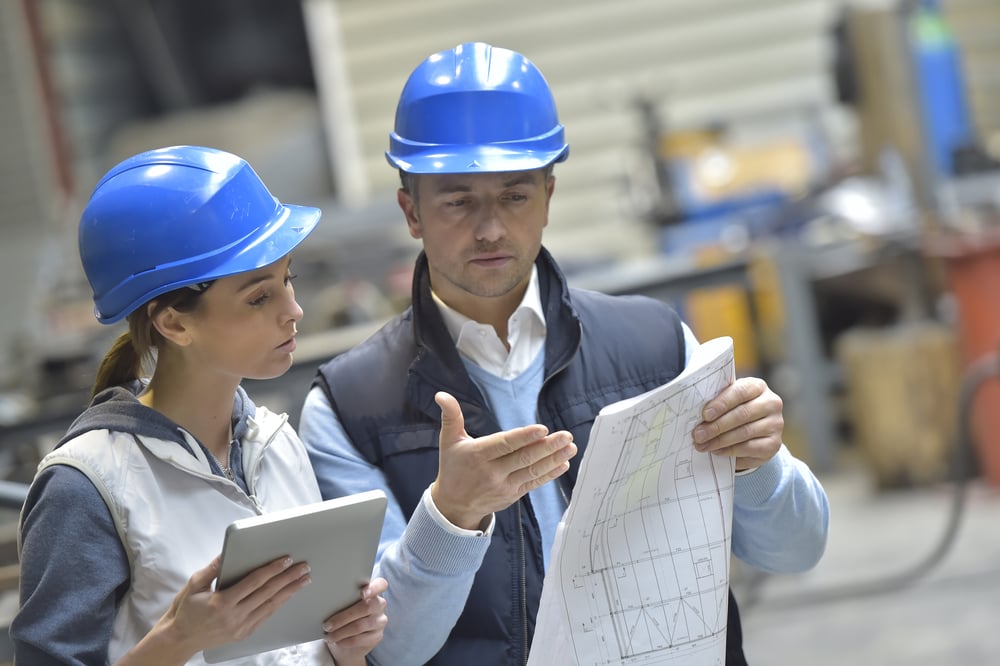 Ingenieure in einer mechanischen Fabrik lesen Anweisungen