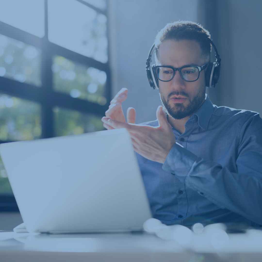 Mann mit Kopfhörern klatscht in die Hände, während er sich ein Webinar auf einem Laptop ansieht