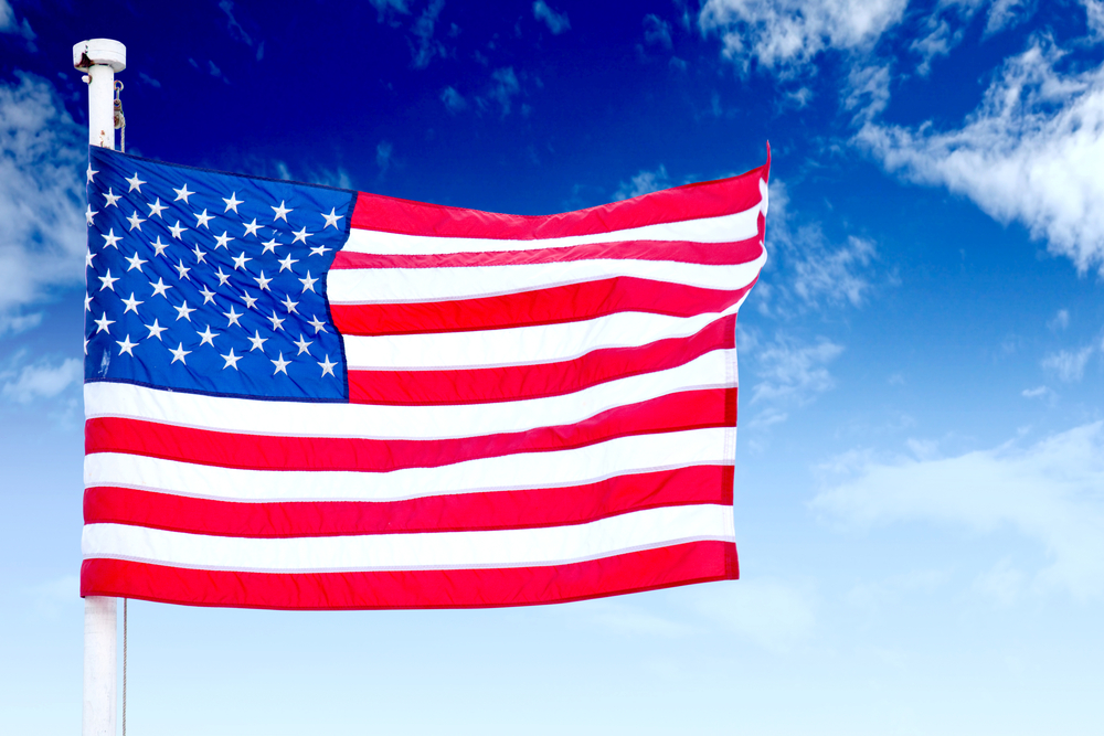 Bild der amerikanischen Flagge Wellen im Wind mit blauem Himmel im Hintergrund 