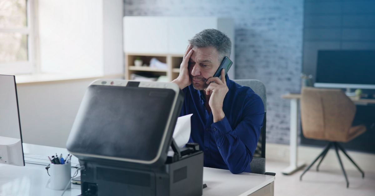 Verwirrter Mann am Telefon mit Blick auf den Drucker