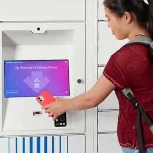 Schülerin benutzt intelligentes Paketfach mit Telefon Schülerin benutzt intelligentes Paketfach mit Telefon